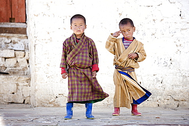 Two boys in front of white wall at Ura Lhakhang, Ura village, near Jakar, Bumthang, Bhutan, Asia