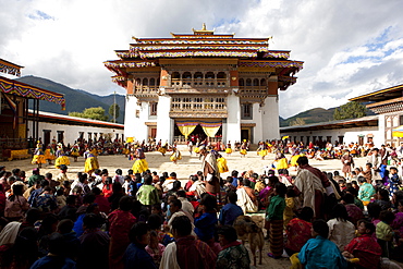 View over crowds of spectators to the main courtyard during a masked dance by Buddhist monks at Gangtey Tsechu at Gangte Goemba, Gangte, Phobjikha Valley, Bhutan, Asia