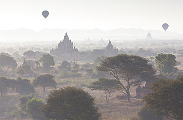 View over the temples of Bagan swathed in early morning mist, with hot air balloon drifting across the scene, from Shwesandaw Paya, Bagan, Myanmar (Burma), Southeast Asia