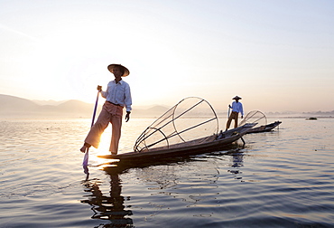 Intha leg rowing fishermen at dawn on Inle Lake who row traditional wooden boats using their leg and fish using nets stretched over conical bamboo frames, Inle Lake, Shan State, Myanmar (Burma), Asia