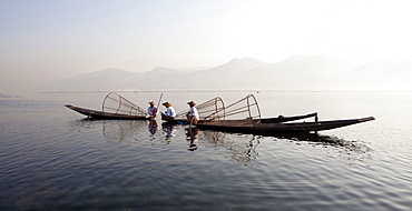 Intha leg rowing fishermen on Inle Lake who row traditional wooden boats using their leg and fish using nets stretched over conical bamboo frames, Inle Lake, Shan State, Myanmar (Burma), Asia