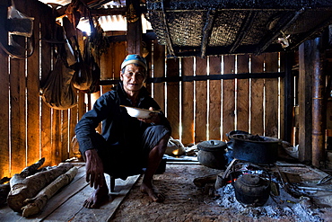 Animist man of the Ann tribe eating in his home by open fire, Panlor village, near Kengtung (Kyaingtong), Shan State, Myanmar (Burma), Asia