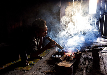 Man of the Palaung tribe cooking on open fire in his home in village near Kengtung (Kyaingtong), Shan State, Myanmar (Burma), Asia