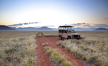 Land rover game vehicle parked by sand road at sunrise, Namib Rand game reserve, Namib Naukluft Park, Namibia, Africa