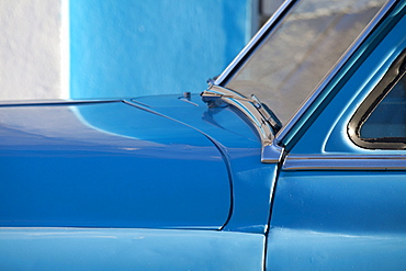 Detail of vintage blue American car against painted blue wall, Cienfuegos, Cuba, West Indies, Central America 