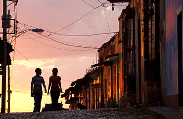 Two young people in silhouette at sunset on cobbled street with colourful orange sky behind, Trinidad, UNESCO World Heritage Site, Cuba, West Indies, Central America 