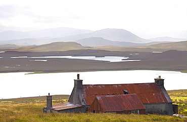 Farmhouse with red iron roof overlooking lochs and mountains off the A858 south of Carloway, Isle of Lewis, Outer Hebrides, Scotland, United Kingdom, Europe 