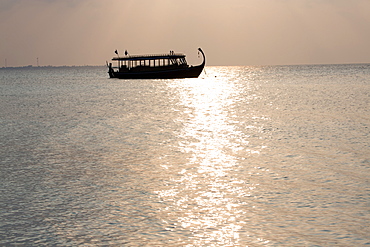 Wooden boat in silhouette at sunset, off Dhuni Kolhu, Baa Atoll, Republic of Maldives, Indian Ocean, Asia