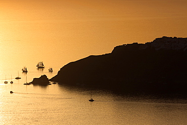 Sunset over the sea with boats and cliffs in silhouette near Oia, from Imerovigli, Santorini, Cyclades, Greek Islands, Greece, Europe