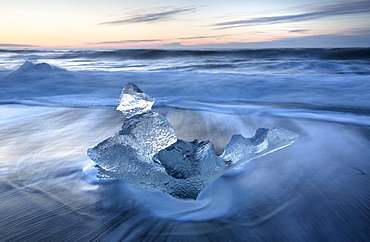 Glassy pieces of ice on volcanic black sand beach at sunrise, near Jokulsarlon Lagoon, South Iceland, Polar Regions