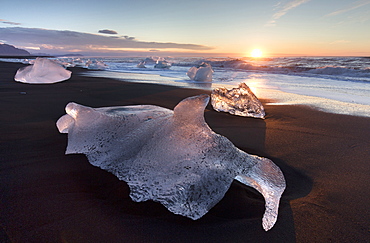 Glassy pieces of ice on volcanic black sand beach at sunrise, near Jokulsarlon Lagoon, South Iceland, Polar Regions