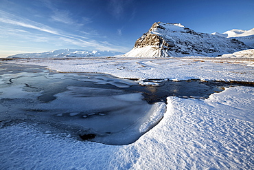 Snow covered landscape in winter with frozen pool, mountain and Vatnajokull Glacier, near Jokulsarlon Lagoon, South Iceland, Polar Regions