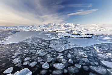 Frozen Jokulsarlon Glacial Lagoon in winter with ice in the foreground and snow covered distant mountains, South Iceland, Polar Regions