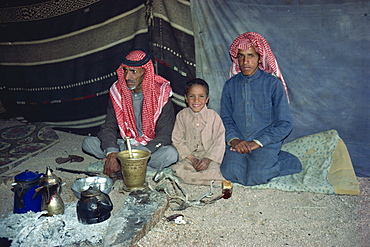 Portrait of three Bedouin sitting inside tent with tea or coffee pots and glasses in Wadi Rum, Jordan, Middle East