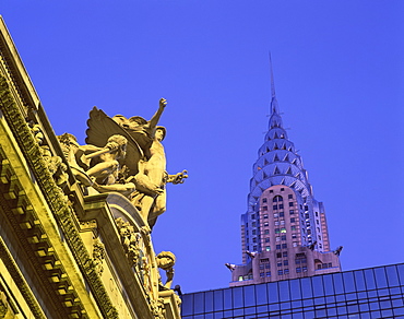 Close-up of statues on top of Grand Central Station, with the Chrysler Building in the background, taken in the evening in New York, United States of America, North America