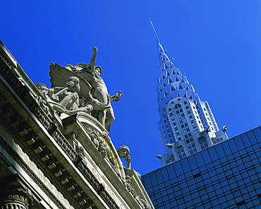 Close-up of statues on top of Grand Central Station, with the Chrysler Building in the background, taken in the evening in New York, United States of America, North America