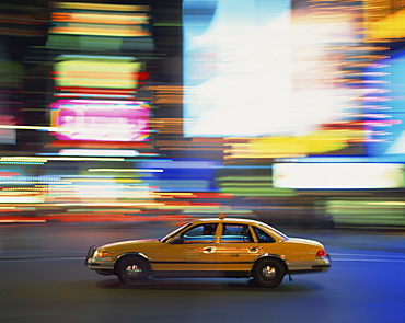 Yellow cab driving past blurred neon lights at night in Times Square in New York, United States of America, North America