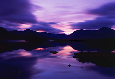 Reflections in the lake of sunset over dark hills of Rannoch Moor in the Highland region of Scotland, United Kingdom, Europe