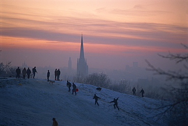 People in a winter landscape with snow on the ground and Norwich Cathedral in the background, Norwich, Norfolk, England, United Kingdom, Europe