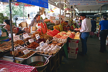 A shopkeeper pointing at fruit on one of the food stalls in the Weekend market in Bangkok, Thailand, Southeast Asia, Asia