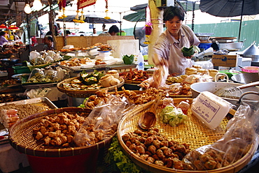 A shopkeeper puts fish cakes on a tray on a stall in the Weekend market in Bangkok, Thailand, Southeast Asia, Asia