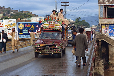 Men riding on the roof of a pick-up taxi in the main street of Mingora in the Swat valley, Pakistan, Asia