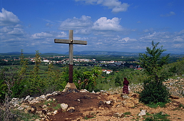 Cross and pilgrim on Apparition Hill, with town beyond, Medjugorje, Bosnia Herzegovina, Europe