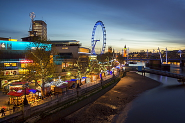 Christmas market is on the South Bank with Big Ben, Houses of Parliament and London Eye at dusk behind, London, England, United Kingdom, Europe