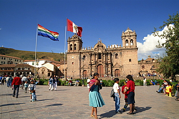 Groups of people and flags flying in front of the cathedral in Cuzco, Peru, South America