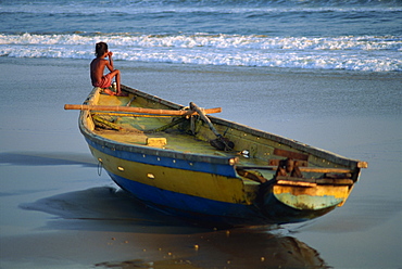 Young boy staring out to sea at dusk, waiting for his father to return from fishing, Puri, Orissa state, India, Asia