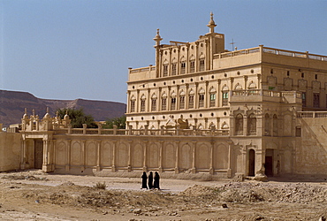 Women in black passing the house of a trader made rich from work in the Far East, Tarim, in the Wadi Hadramaut, south Yemen, Middle East