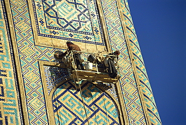 Workers in cradle refurbishing the 17th century Sher Dor Madressa, Registan Square, Samarkand, Uzbekistan, Central Asia, Asia