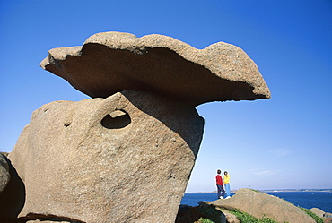 Two figures below precarious granite rocks, Ploumanach, Cotes d'Armor, Brittany, France, Europe