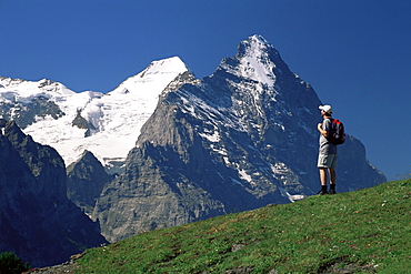 Hiker looking to the snow-covered Monch and the north face of the Eiger, Gross Scheidegg, Grindelwald, Bern, Swiss Alps, Switzerland, Europe