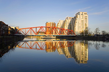 Residential tower blocks and colourful bridge reflected in water, Salford Quays, Salford, Greater Manchester, England, United Kingdom, Europe