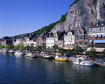 Boats line the waterfront on the River Meuse in the old town of Dinant in the Ardennes, Belgium, Europe