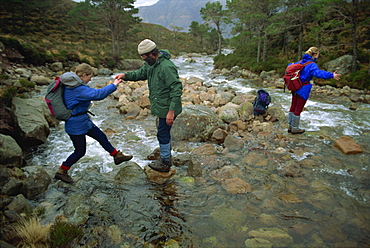 Hikers crossing river in the Ben-Damph Hills, near Loch Torridan, Highlands, Scotland, United Kingdom, Europe