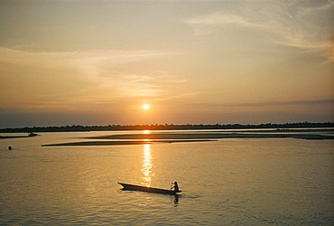 Sunset over Araguava River, Bananal and Karaja Indian in canoe, Brazil, South America