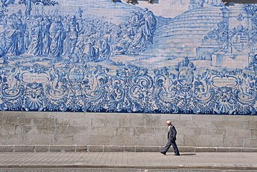 Man walks by the azulejo tile panel of the Carmo church in Oporto, Portugal, Europe