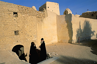 Monk and guest by monastery walls, St. Antony's (St. Anthony's) Coptic Monastery, Eastern Desert, Egypt, North Africa, Africa