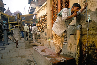 Man drinking from public tap, near Scindia Ghat, Varanasi (Benares), Uttar Pradesh, India, Asia