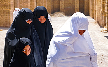 Different generations, different outlooks, grandmother in less common white chador and women and granddaughter in black chadors, Varzaneh, Iran, Middle East