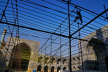 Silhouetted workman setting up marquee for special event in the courtyard of Imam Mosque, Isfahan, Iran, Middle East