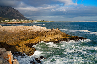 Seascape across stormy sea and rocks in setting sun at Sievers Point, Hermanus, South Africa, Africa