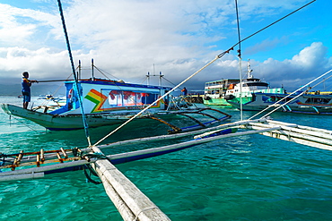 Bangkas (outrigger canoes) and the old ferry compete for landing space at the harbour, Borocay Island, Philippines, Southeast Asia, Asia