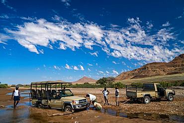 Rescuing safari vehicle stuck in sand of Hoarusib Riverbed, mountain range in background, Puros, north of Sesfontein, Namibia, Africa