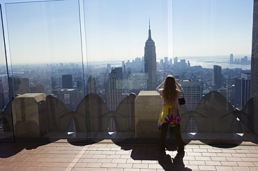 Young tourist looking at the Empire State Building and Manhattan skyline from the Top of the Rock on the Rockefeller Center, New York City, New York, United States of America, North America