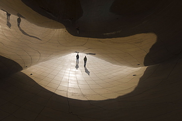 Abstract reflections of people walking under the Cloud Gate sculpture, Millennium Park, Chicago, Illinois, United States of America, North America