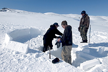 Inuit elder teaches igloo building to young men from the community of Pond Inlet, Nunavut, Canada, North America