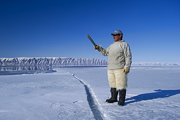 Inuit hunter line fishing at the floe edge for Arctic cod, sculpin and halibut near Herbert Island, Greenland, Denmark, Polar Regions